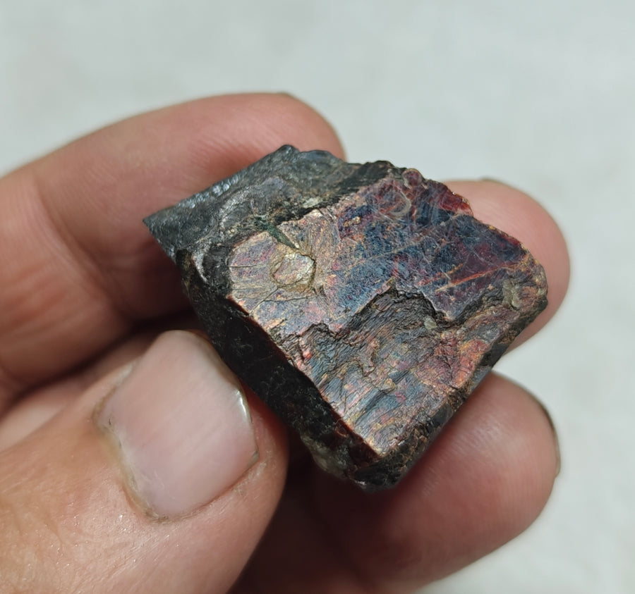 Natural mangano tantalite specimen showing dark metallic surfaces and colourful reflections